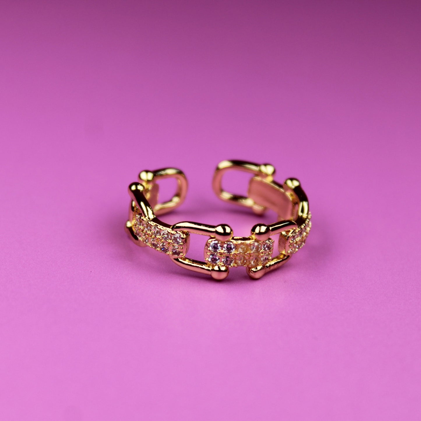 Gold ring with pink gemstones on a pink background