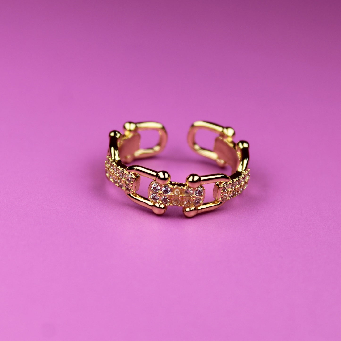 Gold ring with a diamond-like pattern on a pink background
