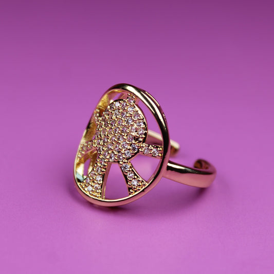Gold ring with a face design on a pink background