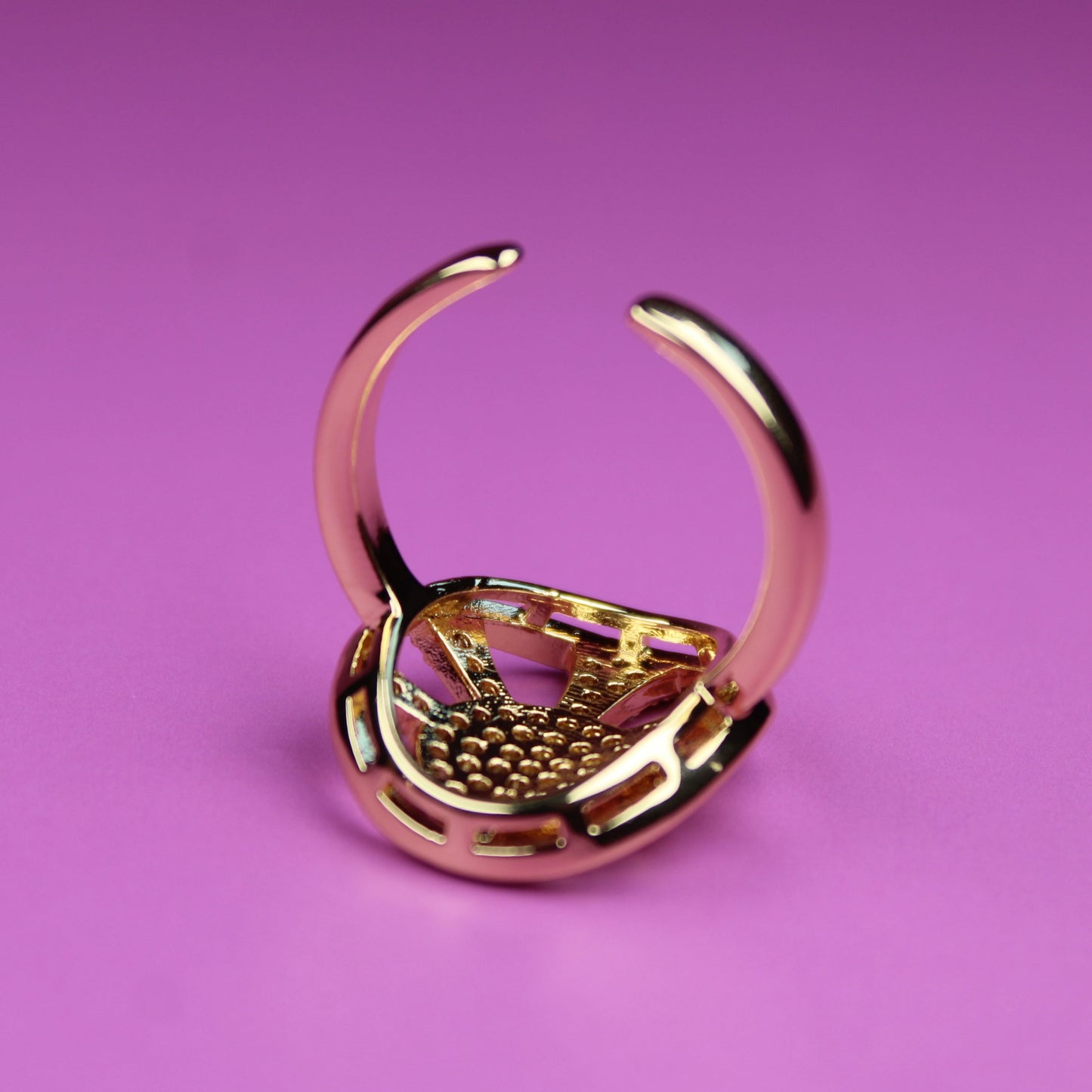 Gold ring holder on a pink background