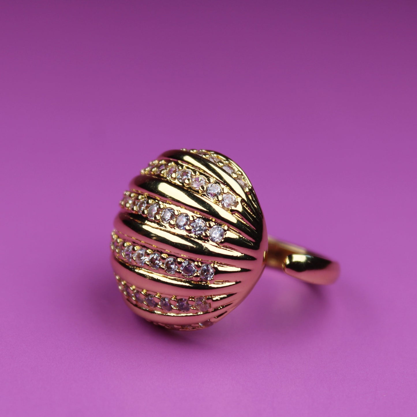 Gold ring with diamond accents on a pink background