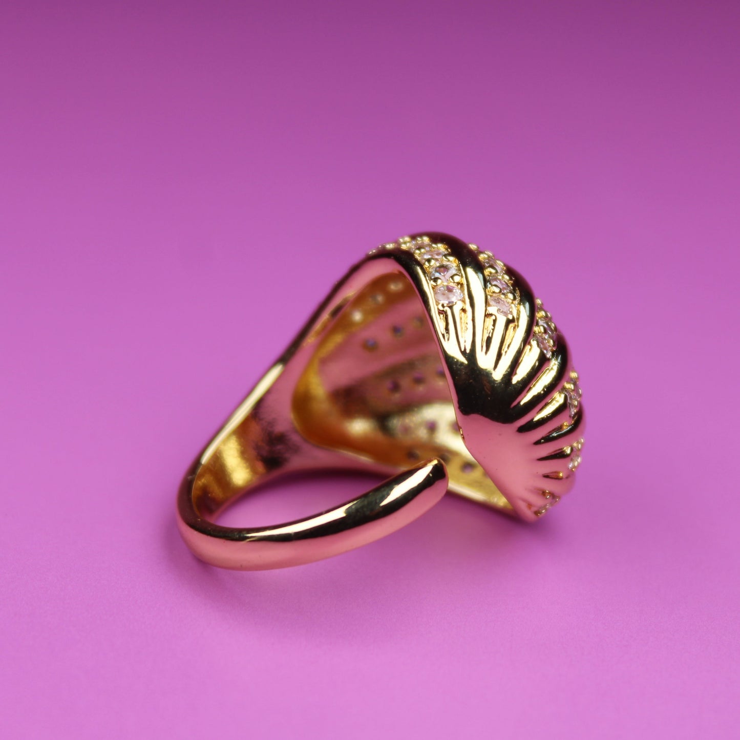 Gold ring with shell design on a pink background