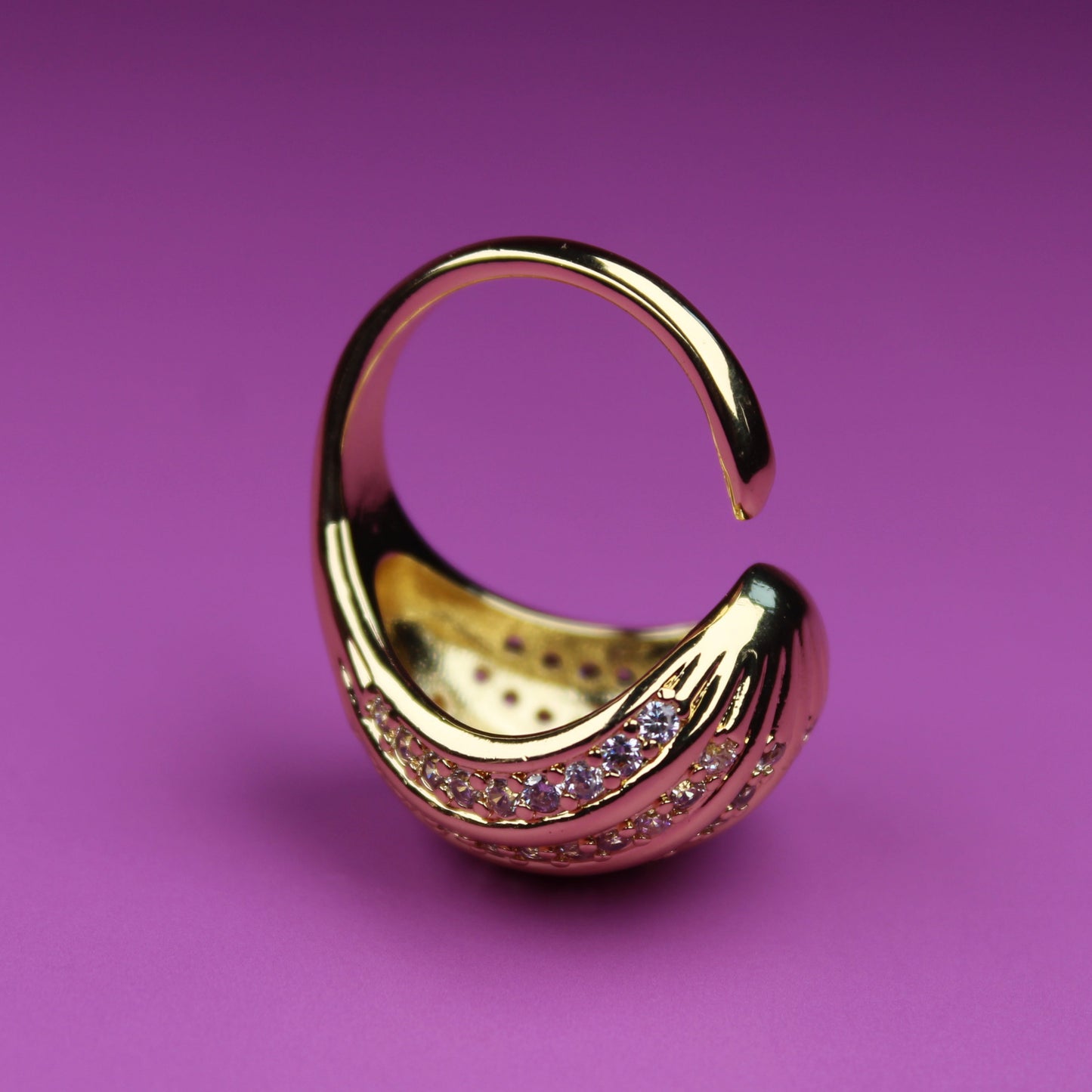 Gold earring with gemstones on a purple background