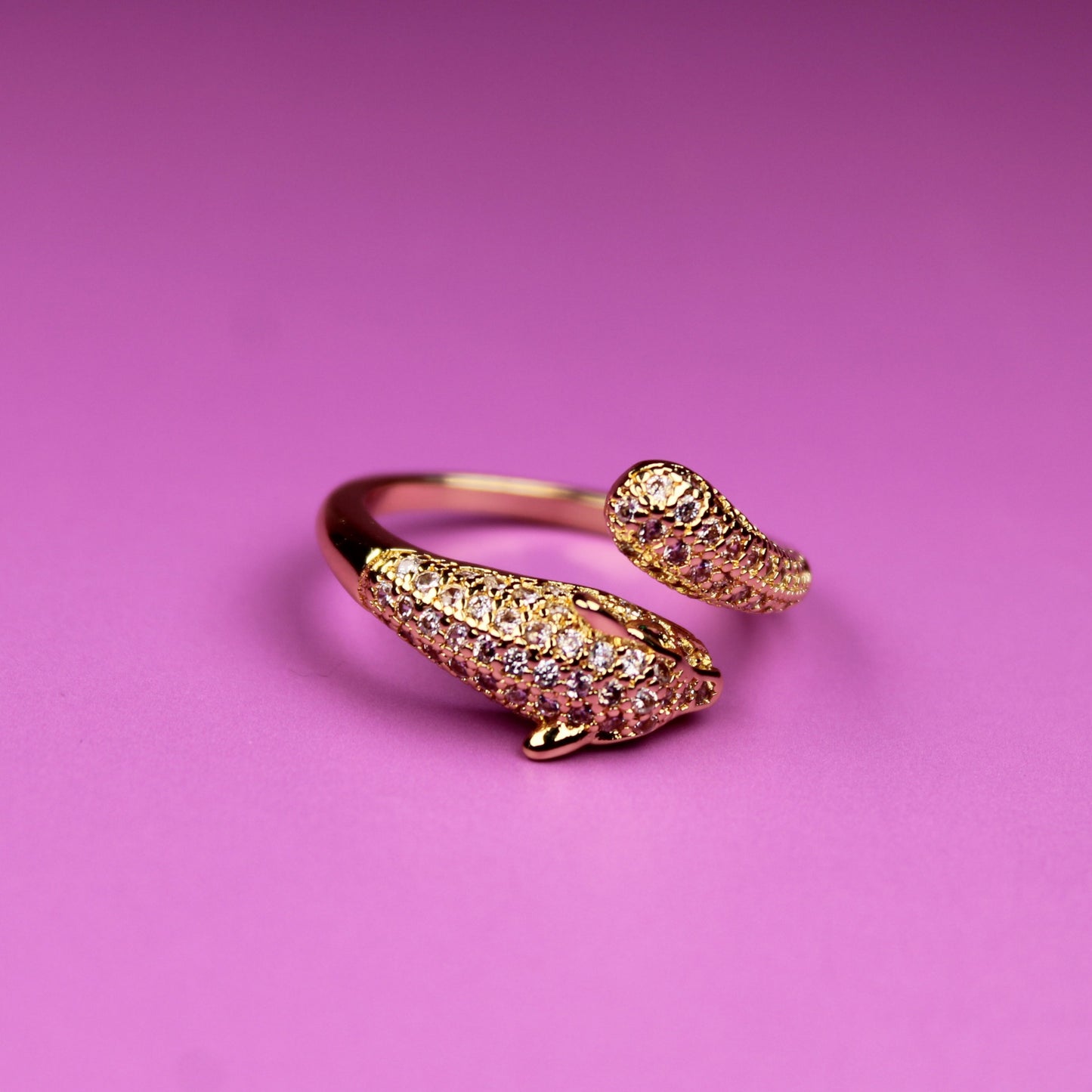 Gold ring with gemstones on a pink background