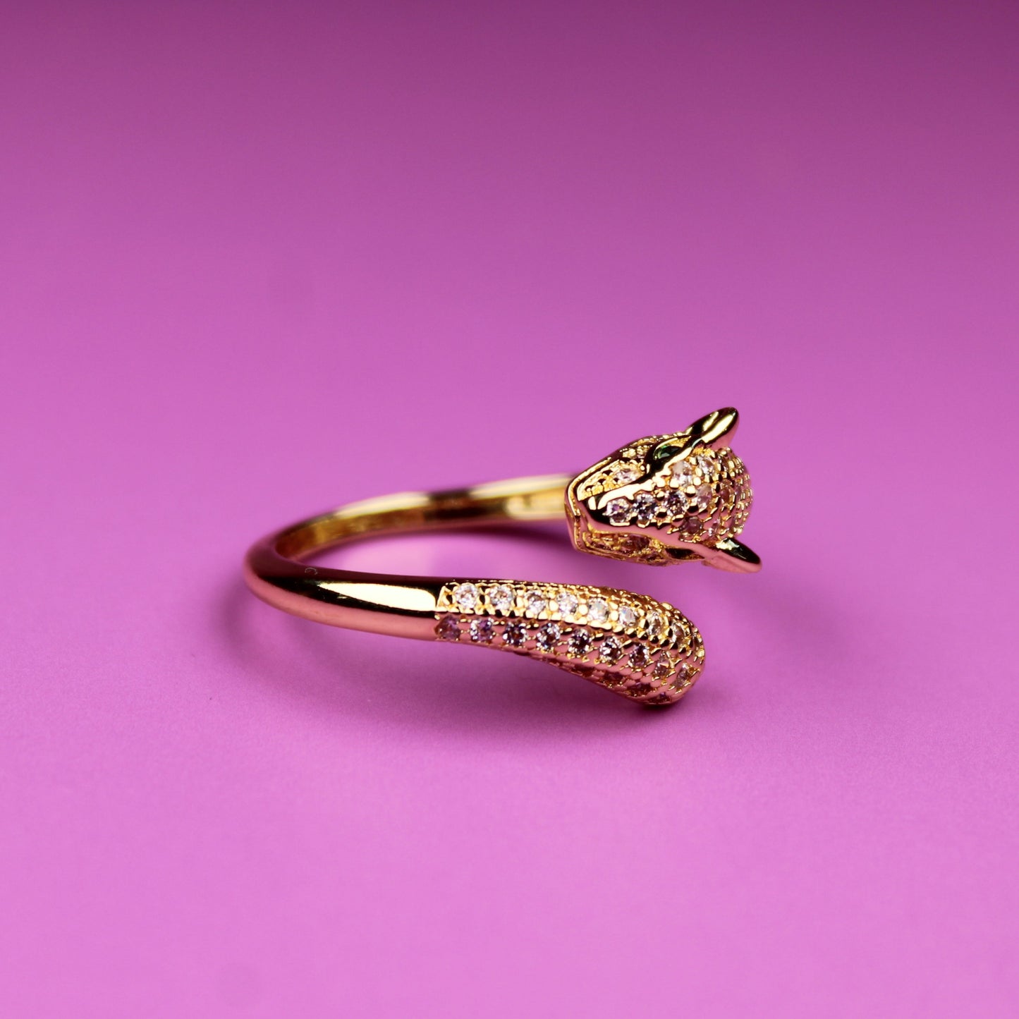 Gold ring with a unique design on a pink background