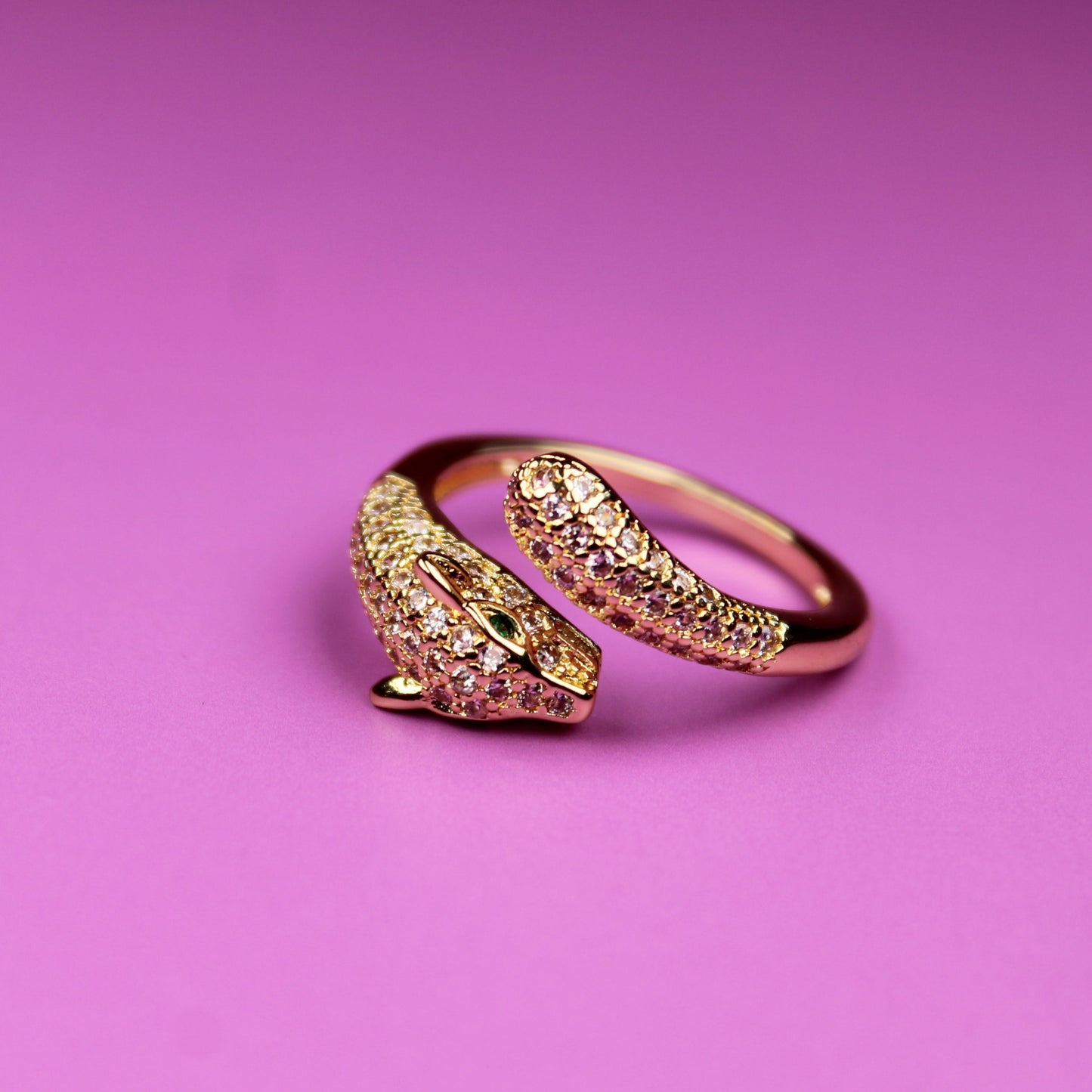 Gold ring with pink gemstone on a pink background