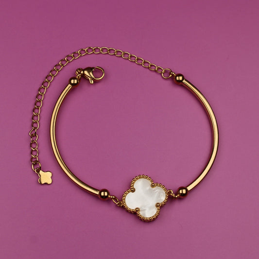 Gold bracelet with a floral clasp on a purple background