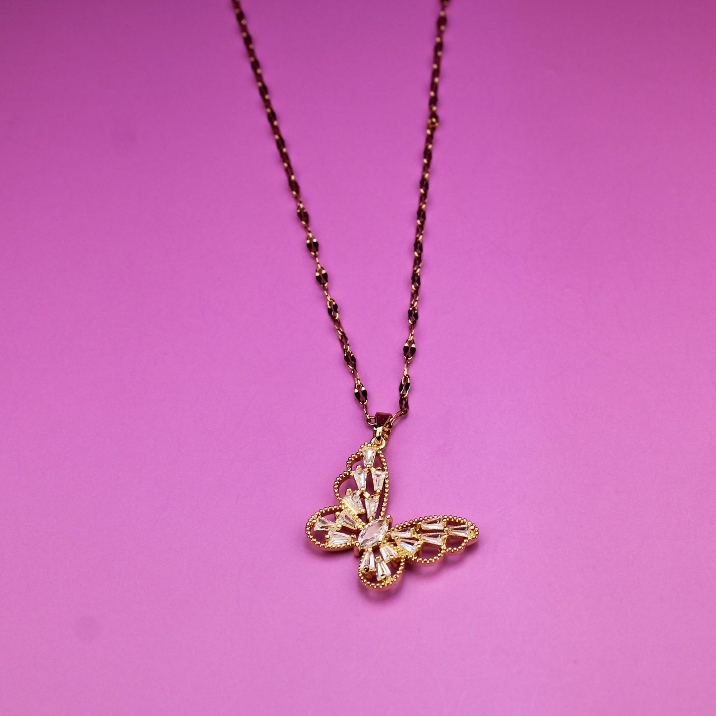 Gold necklace with a cross pendant on a pink background