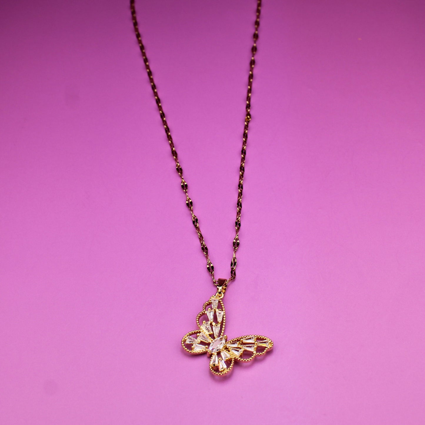 Necklace with a butterfly pendant on a pink background