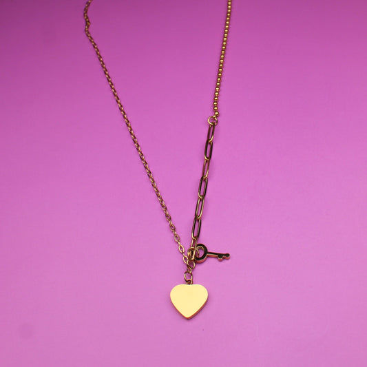 Gold necklace with a heart pendant on a pink background