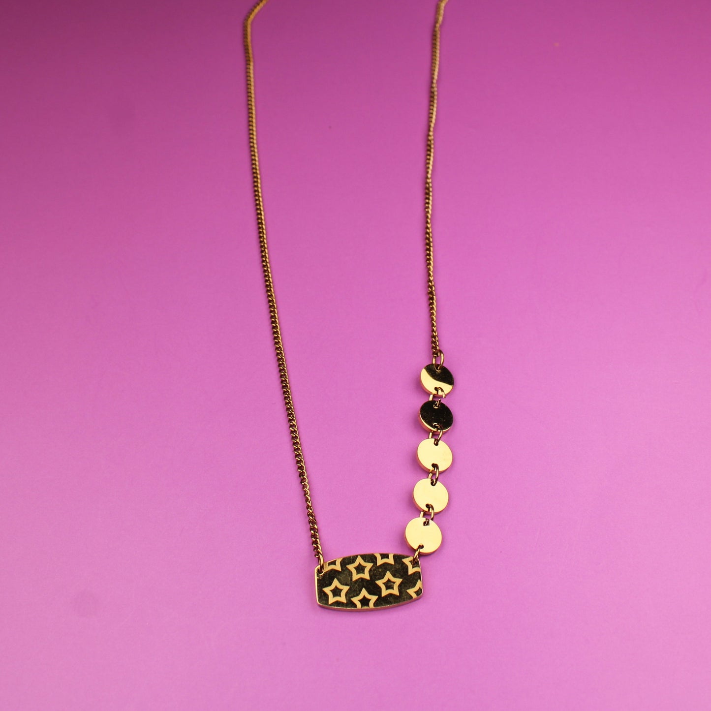 Gold necklace with leopard print pendant on a pink background