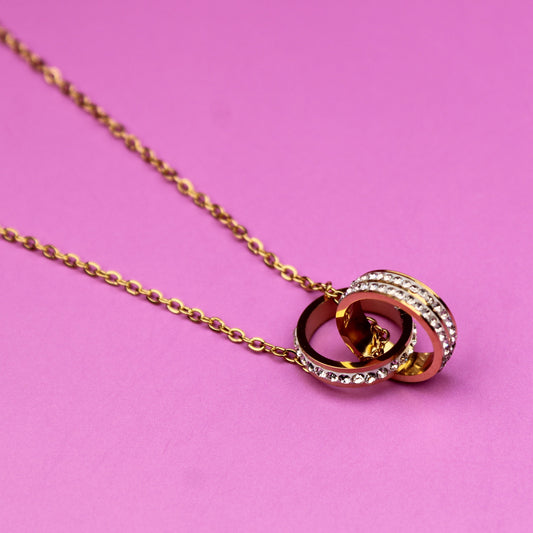 Gold necklace with a circular pendant on a pink background