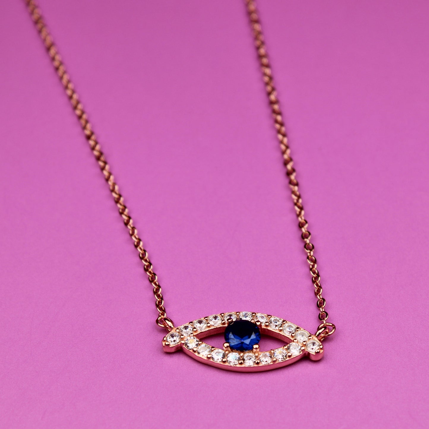 Necklace with eye-shaped pendant on a pink background