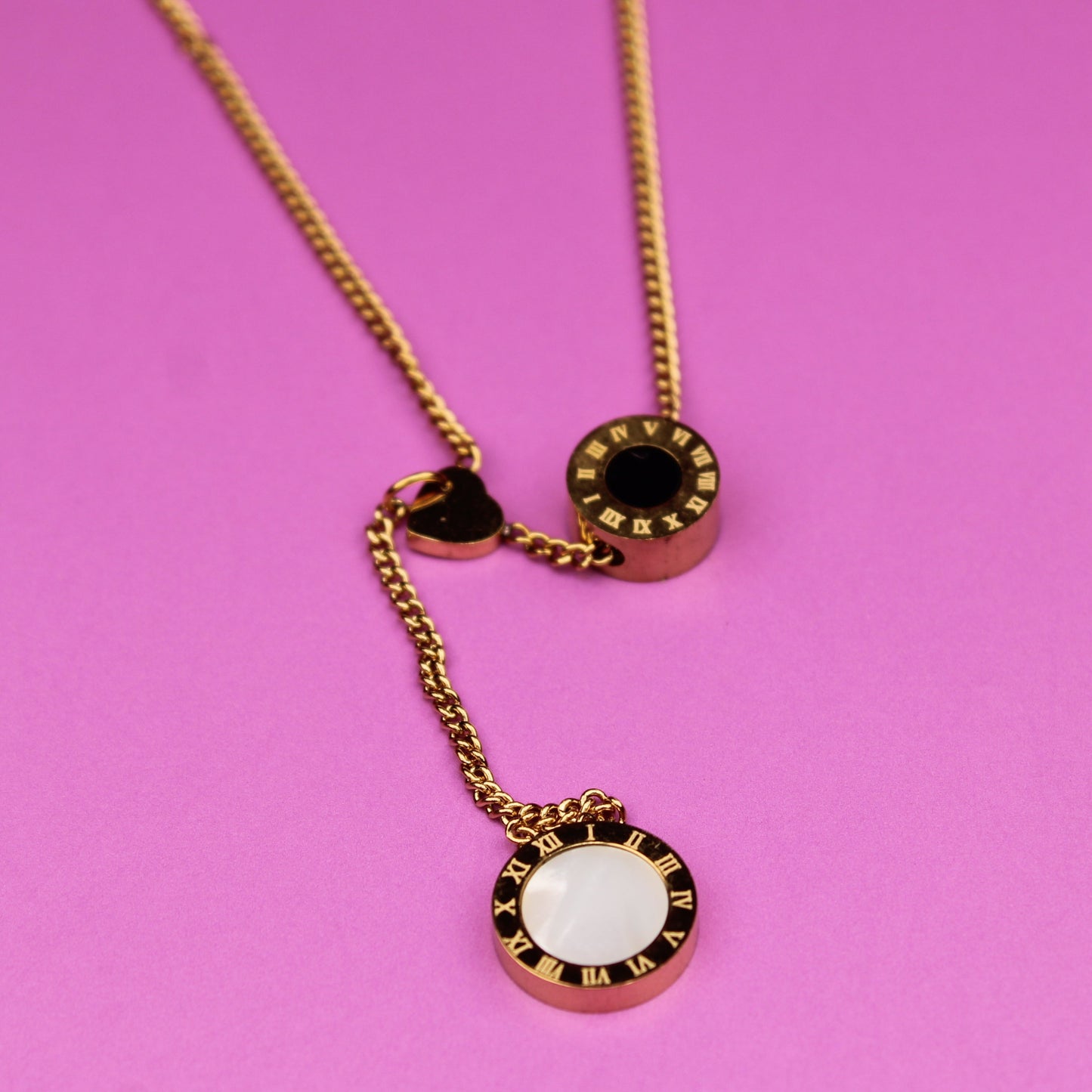 Gold necklace with circular pendant on a pink background