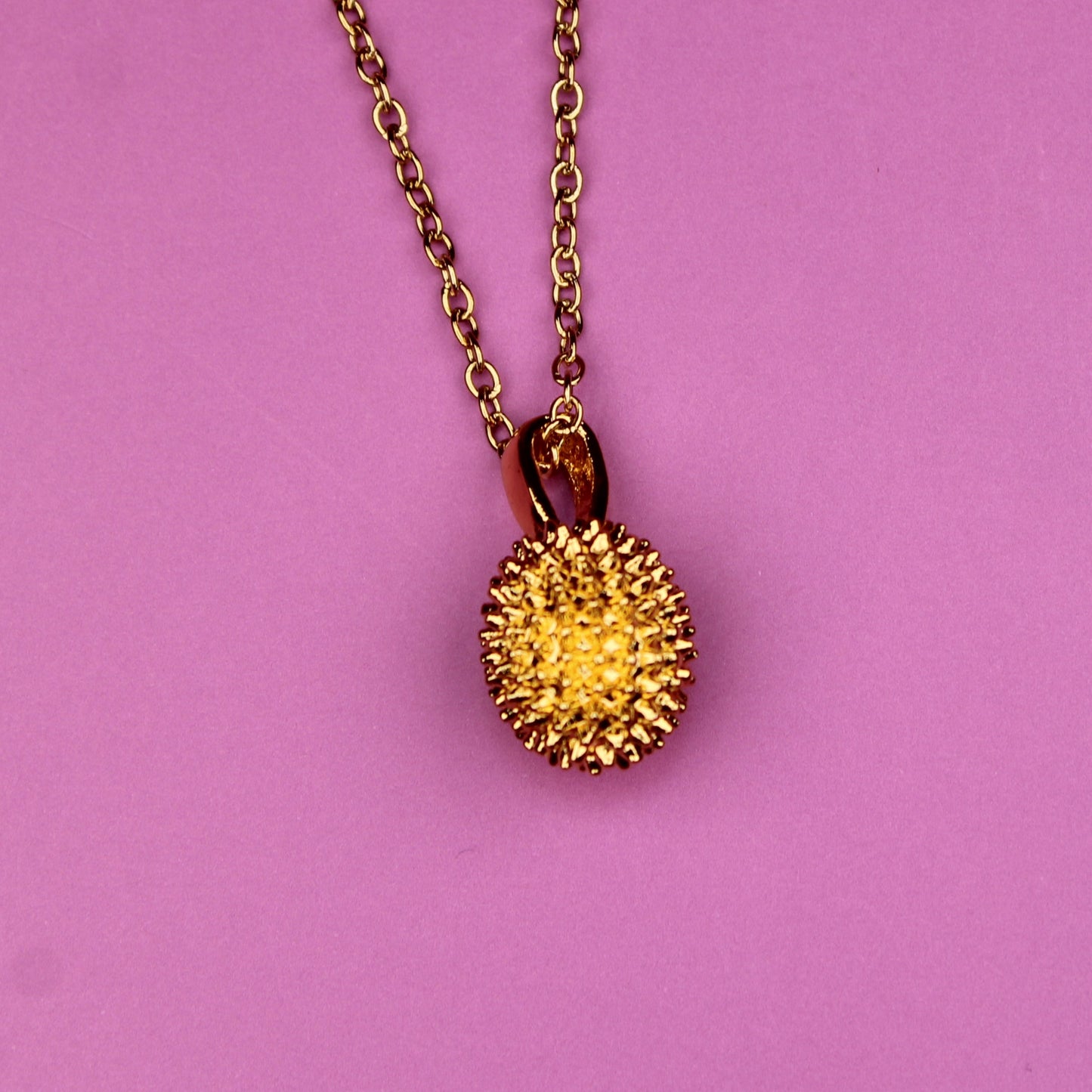 Necklace with a spiky pendant on a pink background