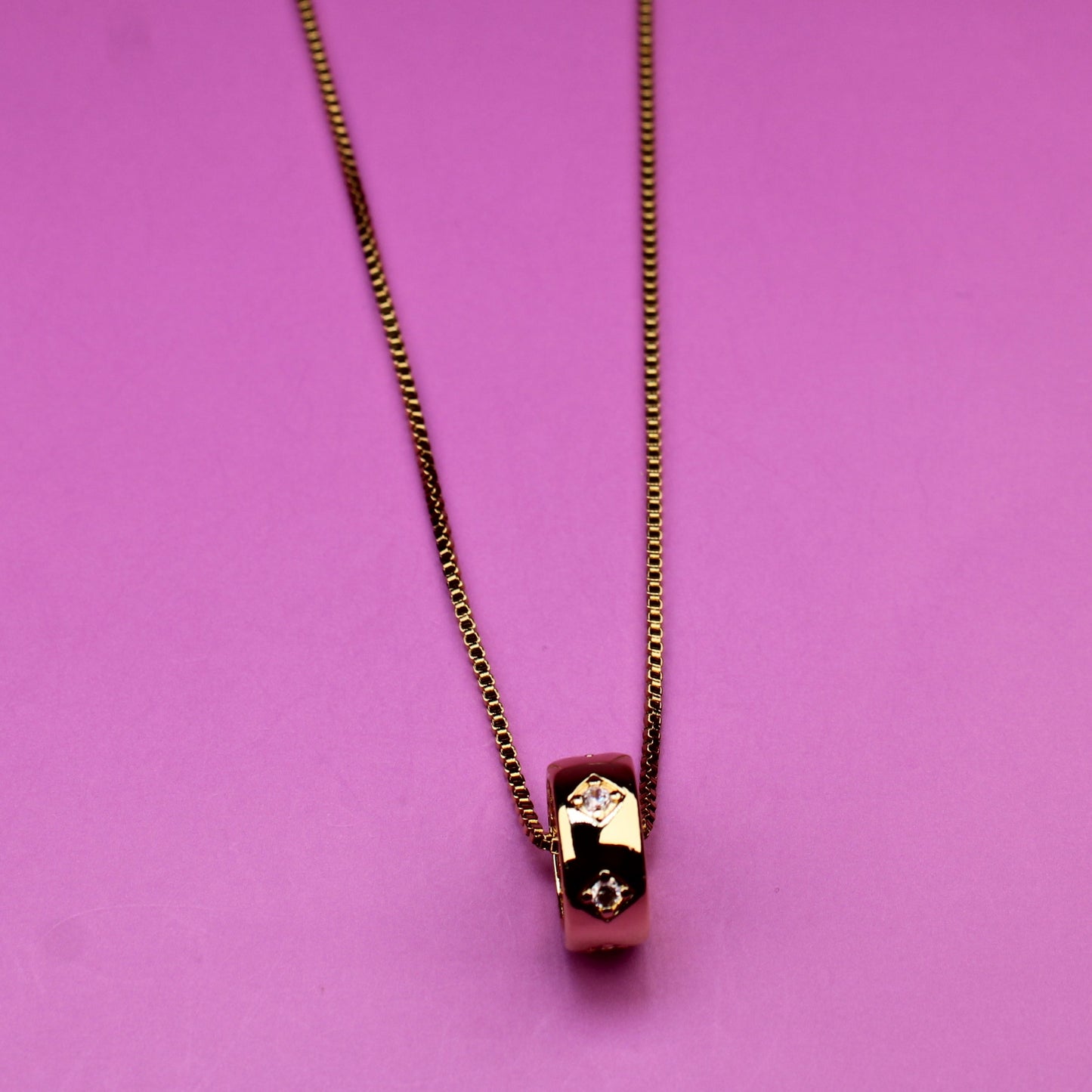 Gold necklace on a pink background