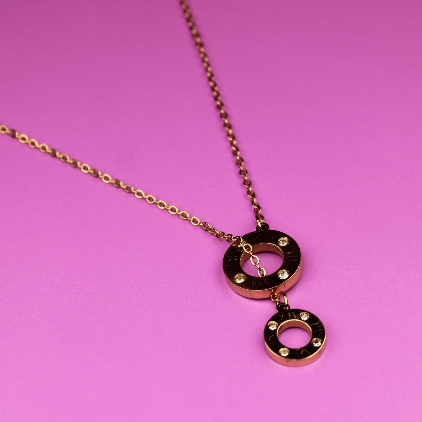 Gold necklace with a pendant on a pink background