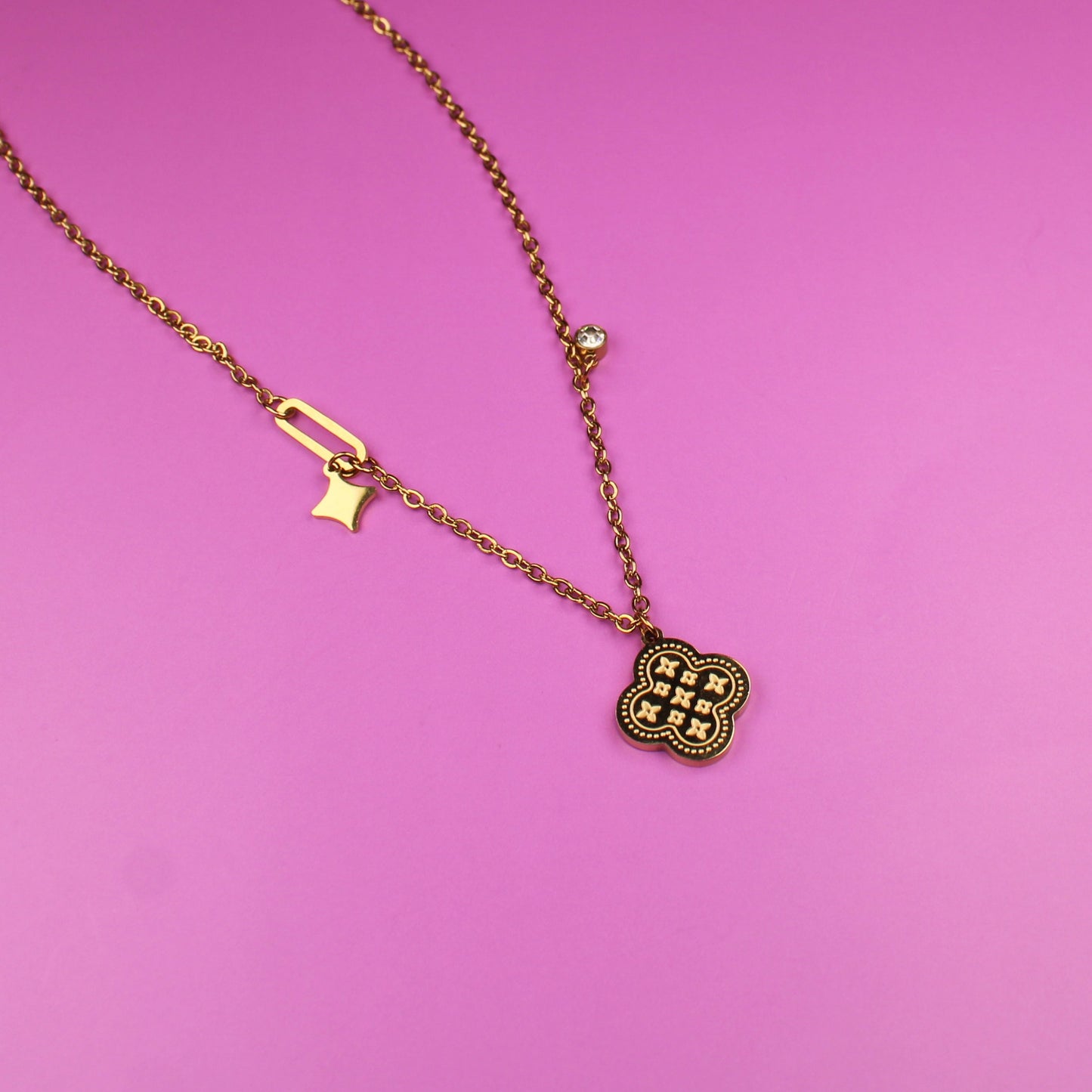 Gold necklace with a lock pendant on a pink surface