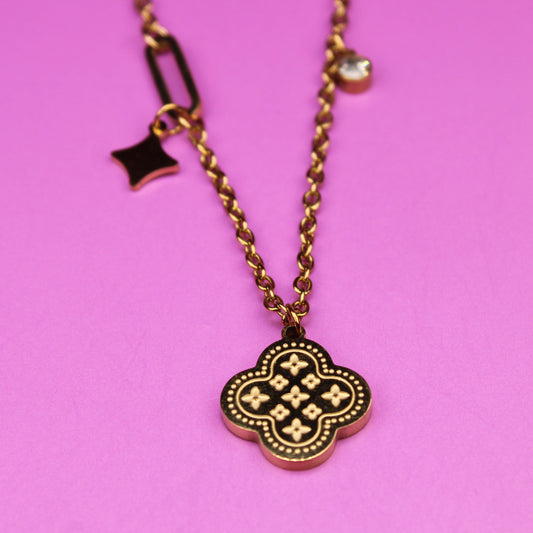 Necklace with a clover-shaped pendant on a pink background