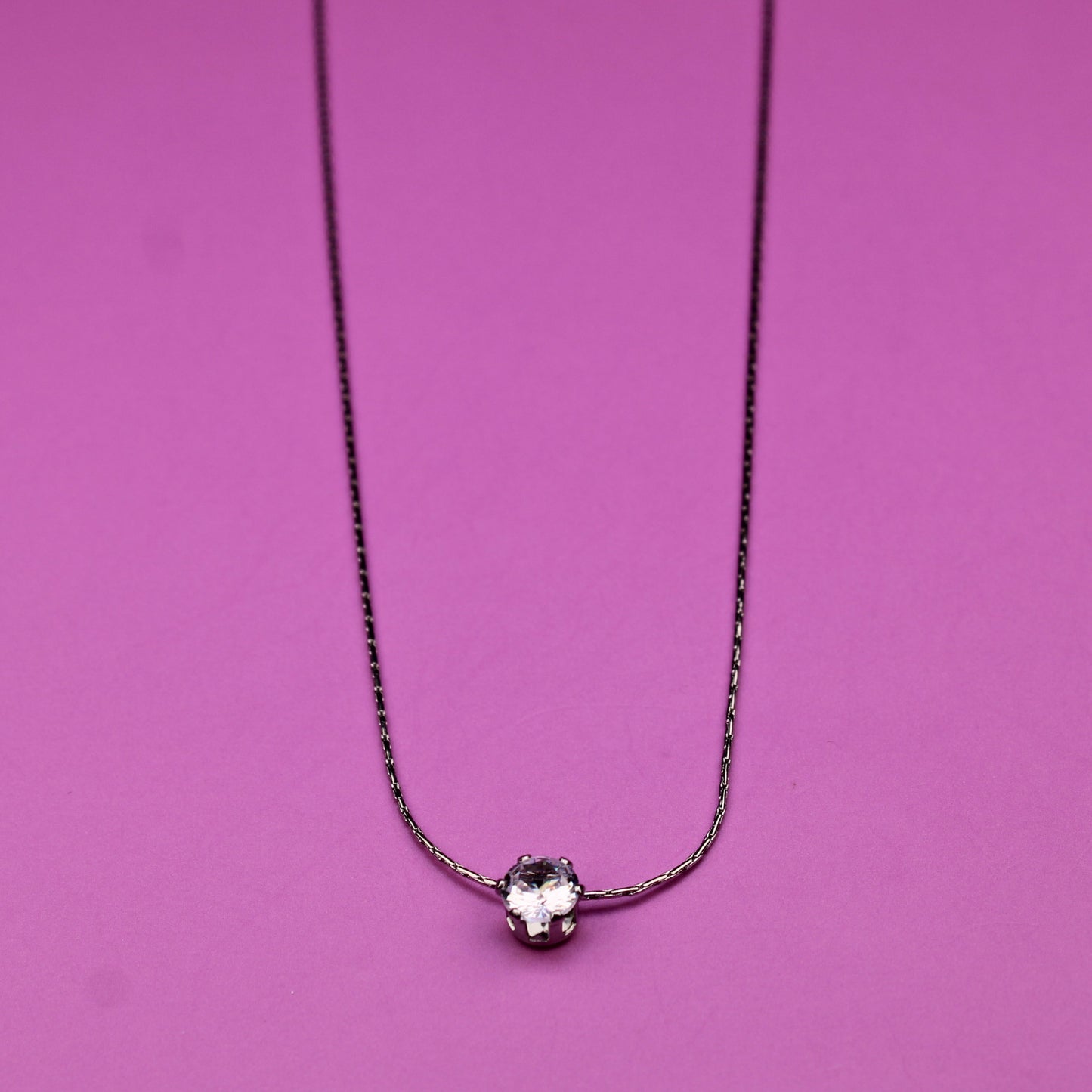 Necklace with a small round pendant on a pink background