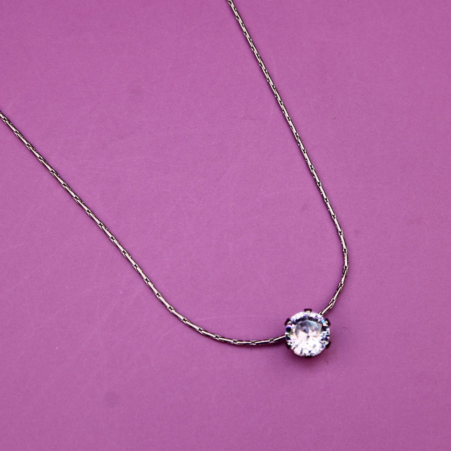 Necklace with a round pendant on a pink background