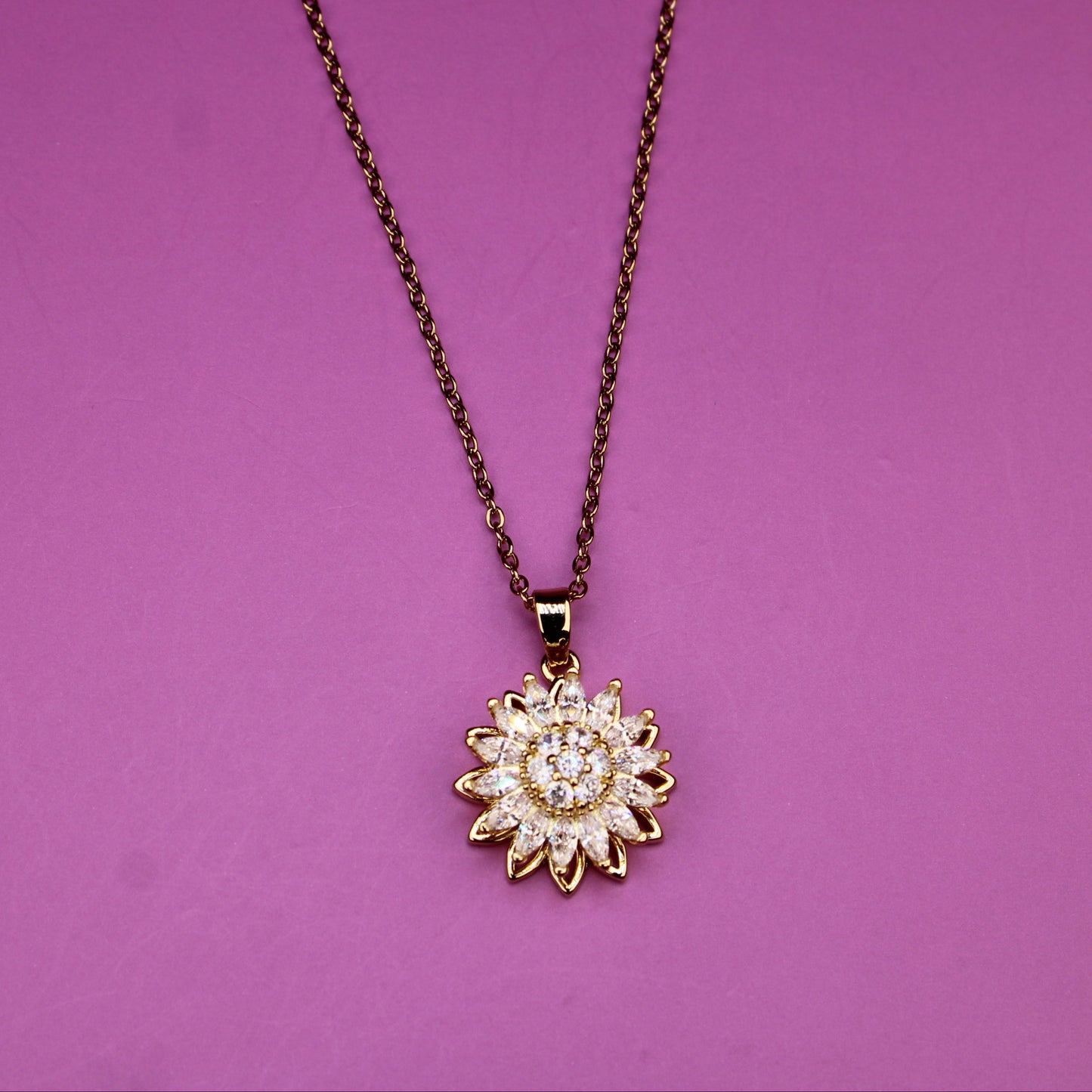 Gold sunflower pendant necklace on a purple background