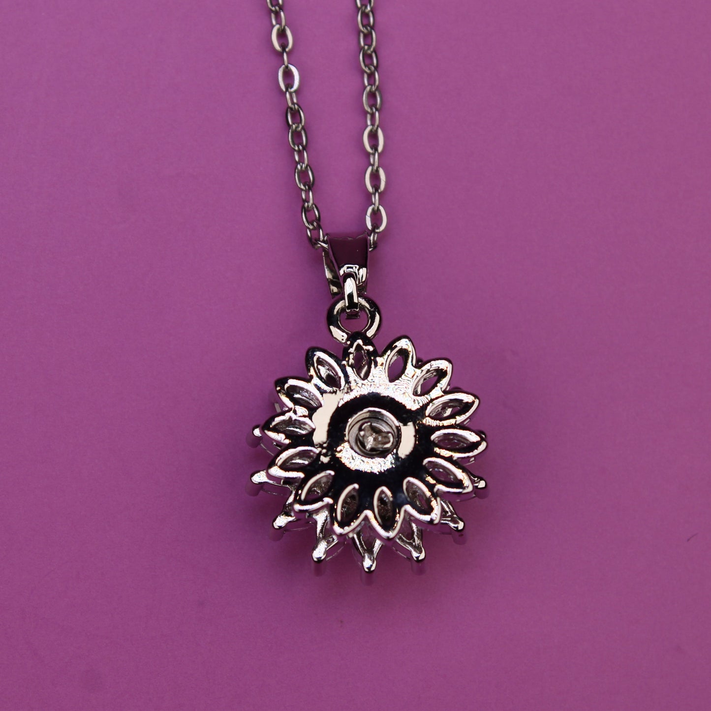 Silver sunflower pendant necklace on a purple background
