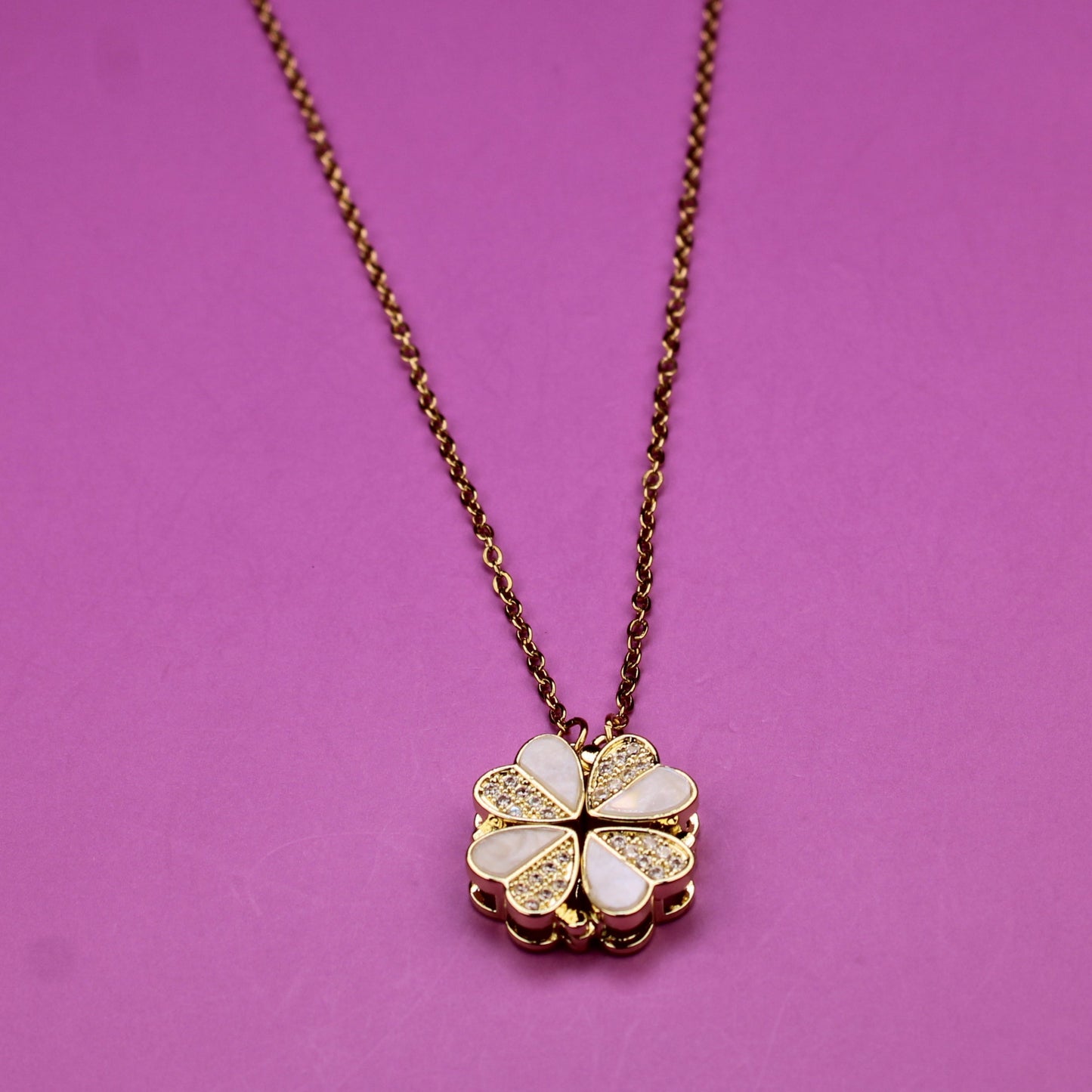 Necklace with a clover-shaped pendant on a pink background
