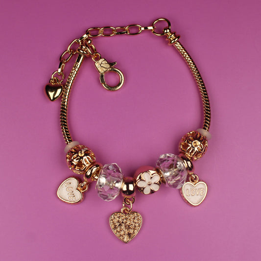 Gold bracelet with heart-shaped charms on a pink background