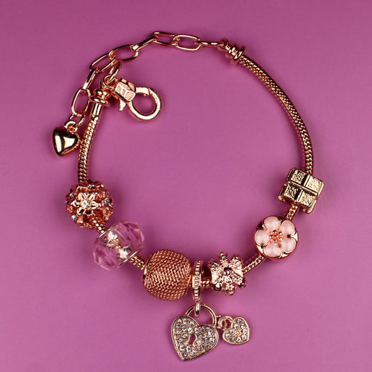 Gold bracelet with charms on a pink background