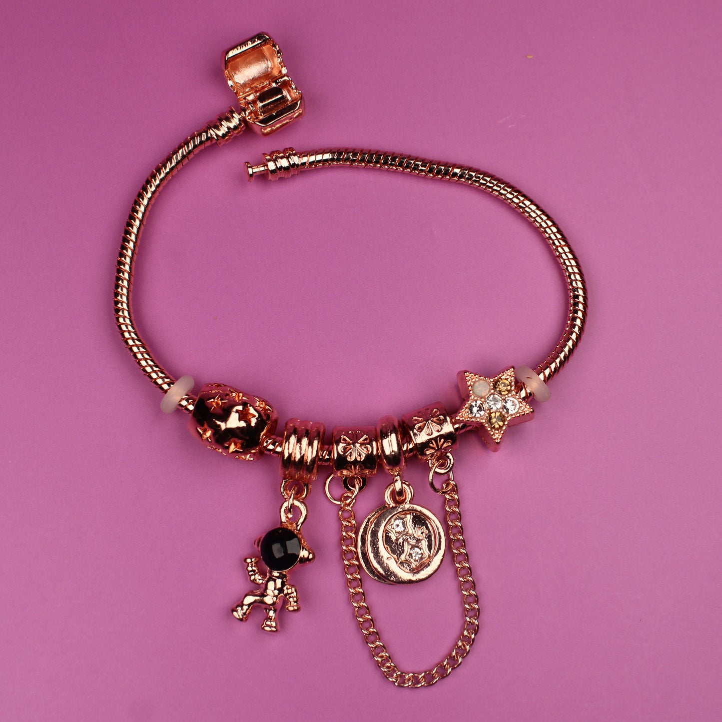Rose gold bracelet with charms on a pink background