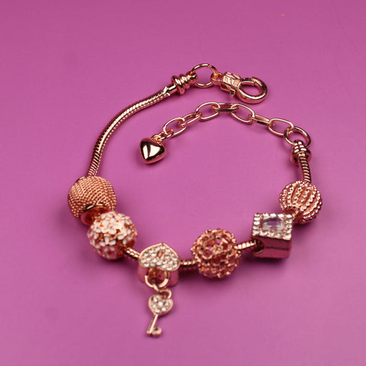 Rose gold bracelet with charms on a pink background