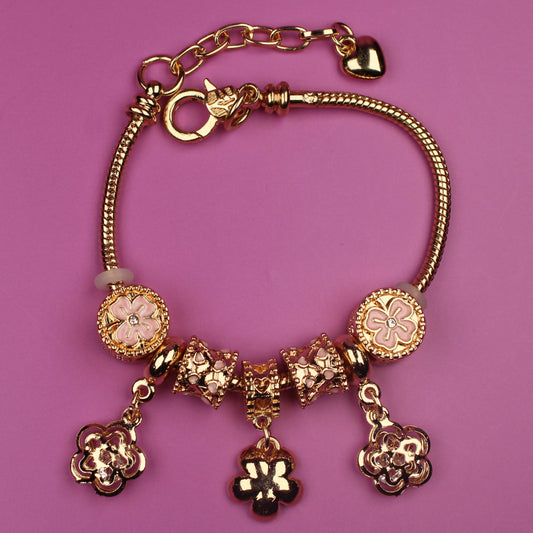 Gold bracelet with charms on a pink background