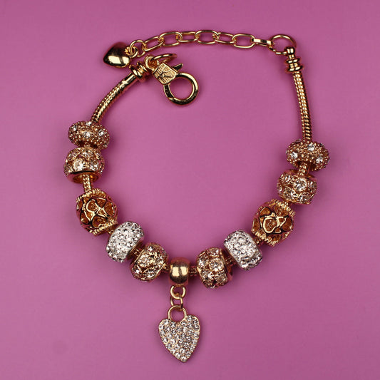 Gold bracelet with charms on a pink background
