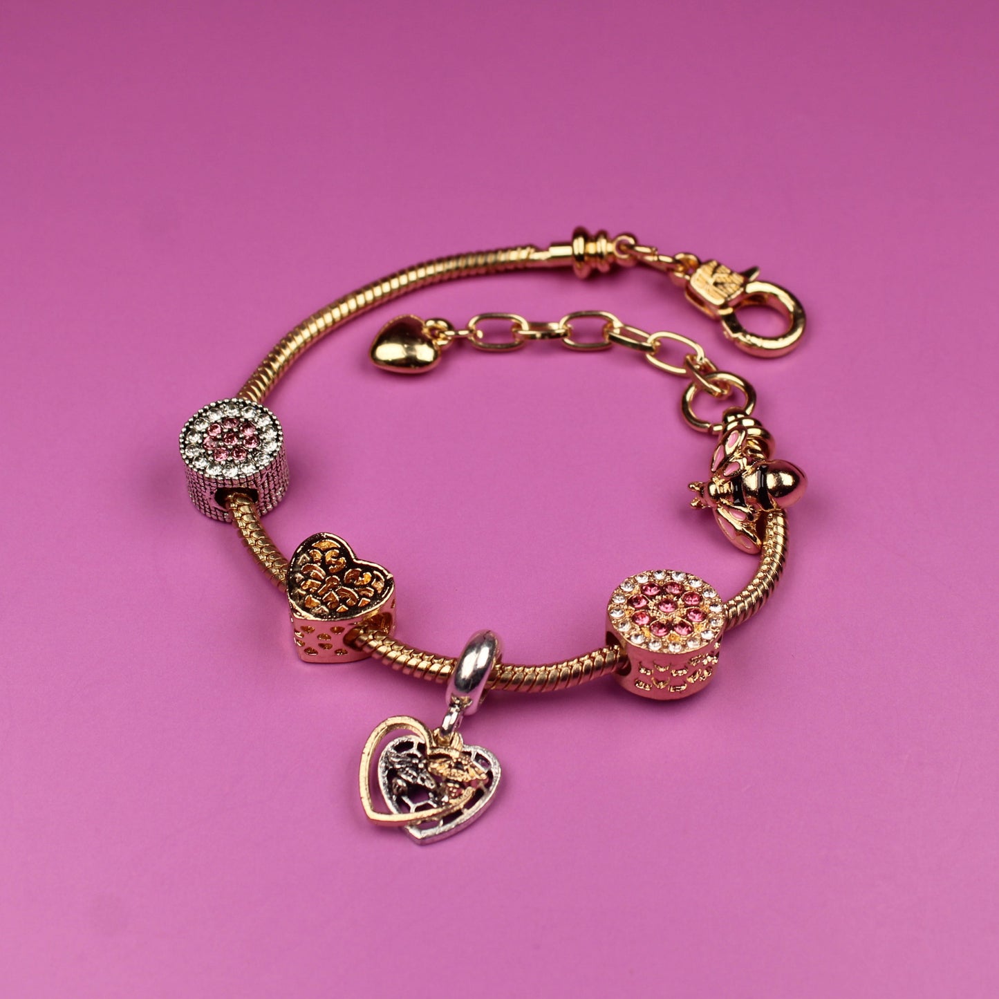 Gold bracelet with charms on a pink background