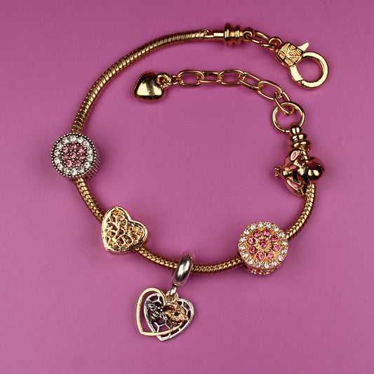 Gold bracelet with heart-shaped charms on a pink background
