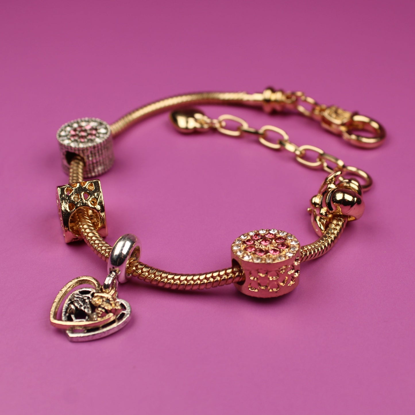 Gold bracelet with charms on a pink background