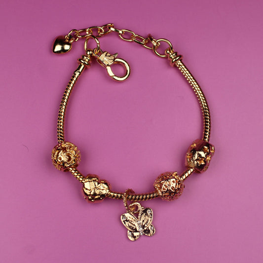 Gold bracelet with charms on a pink background