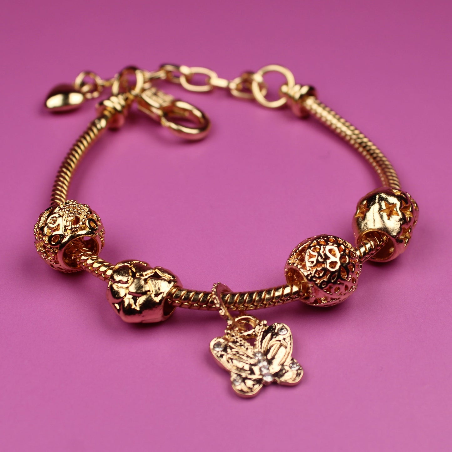 Gold bracelet with charms on a pink background