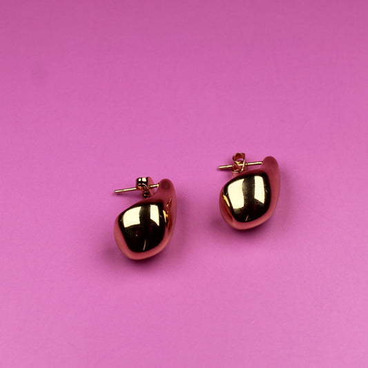 Pair of red heart-shaped earrings on a pink background