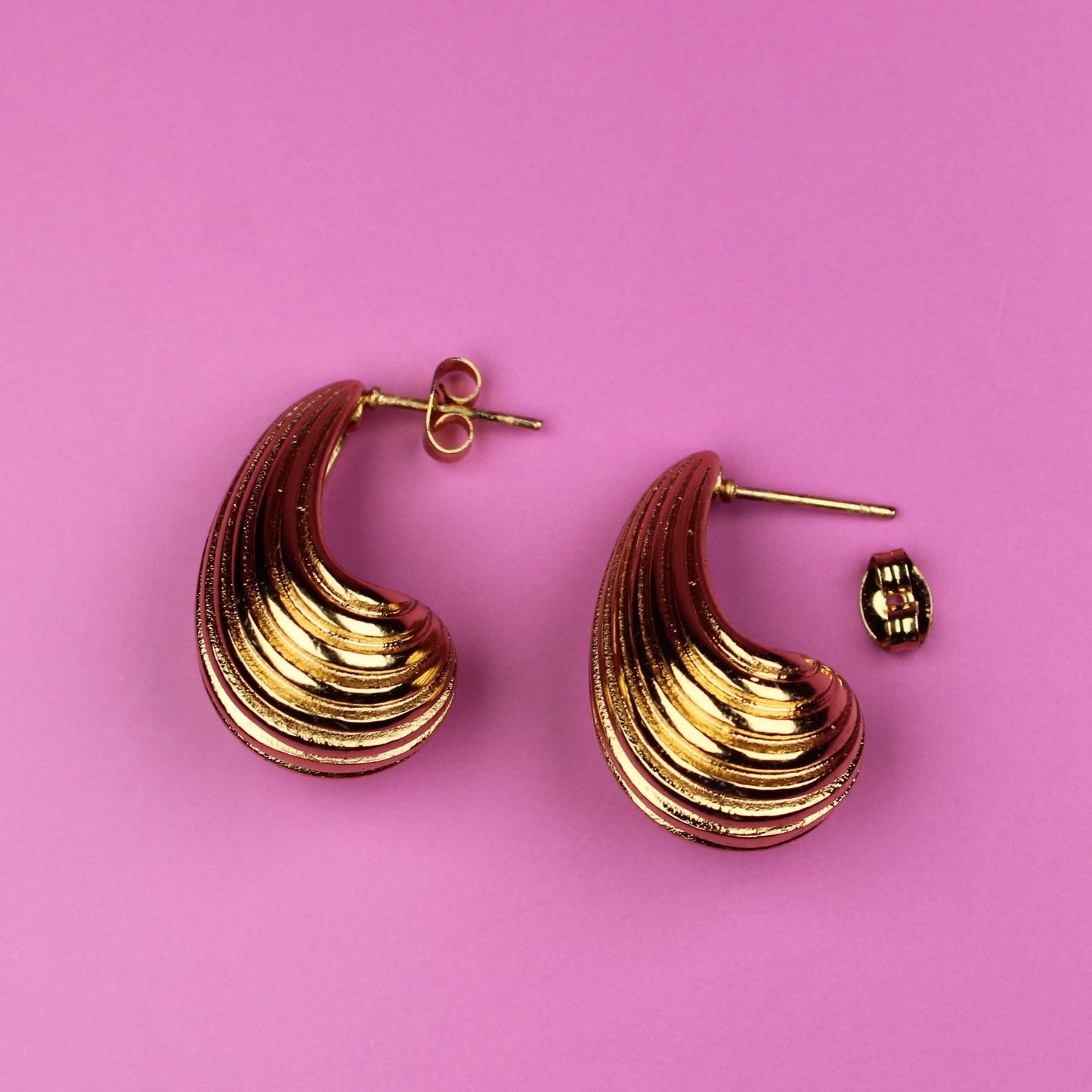 Gold hoop earrings on a pink background