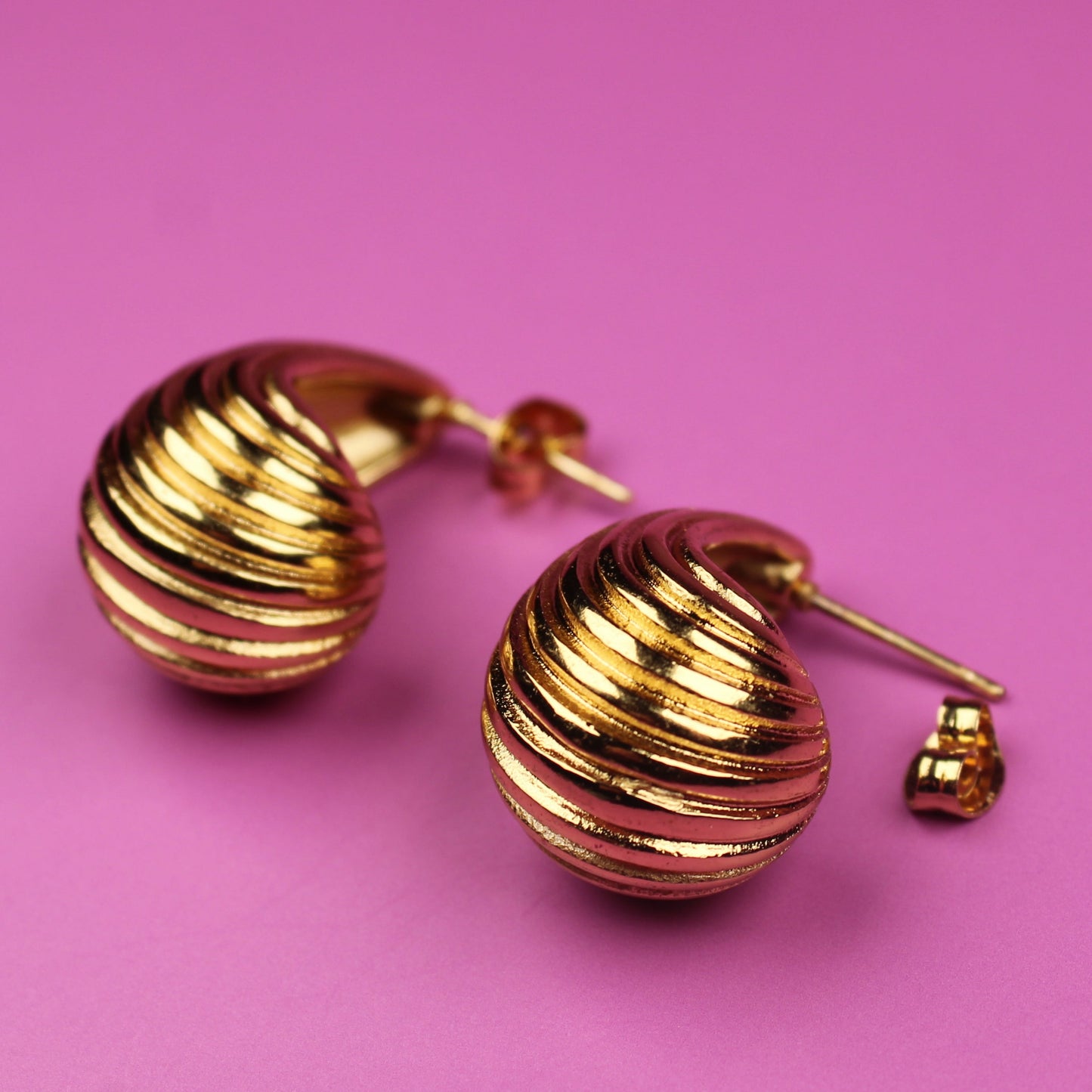 Gold earrings on a pink background
