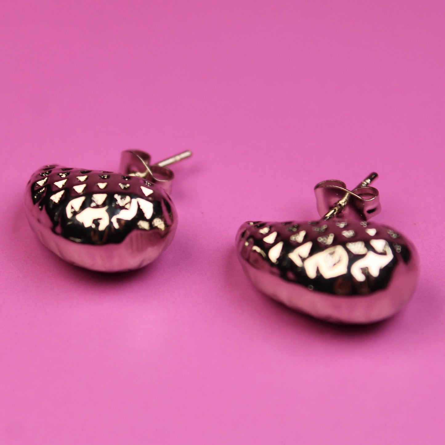 Pink heart-shaped earrings on a pink background