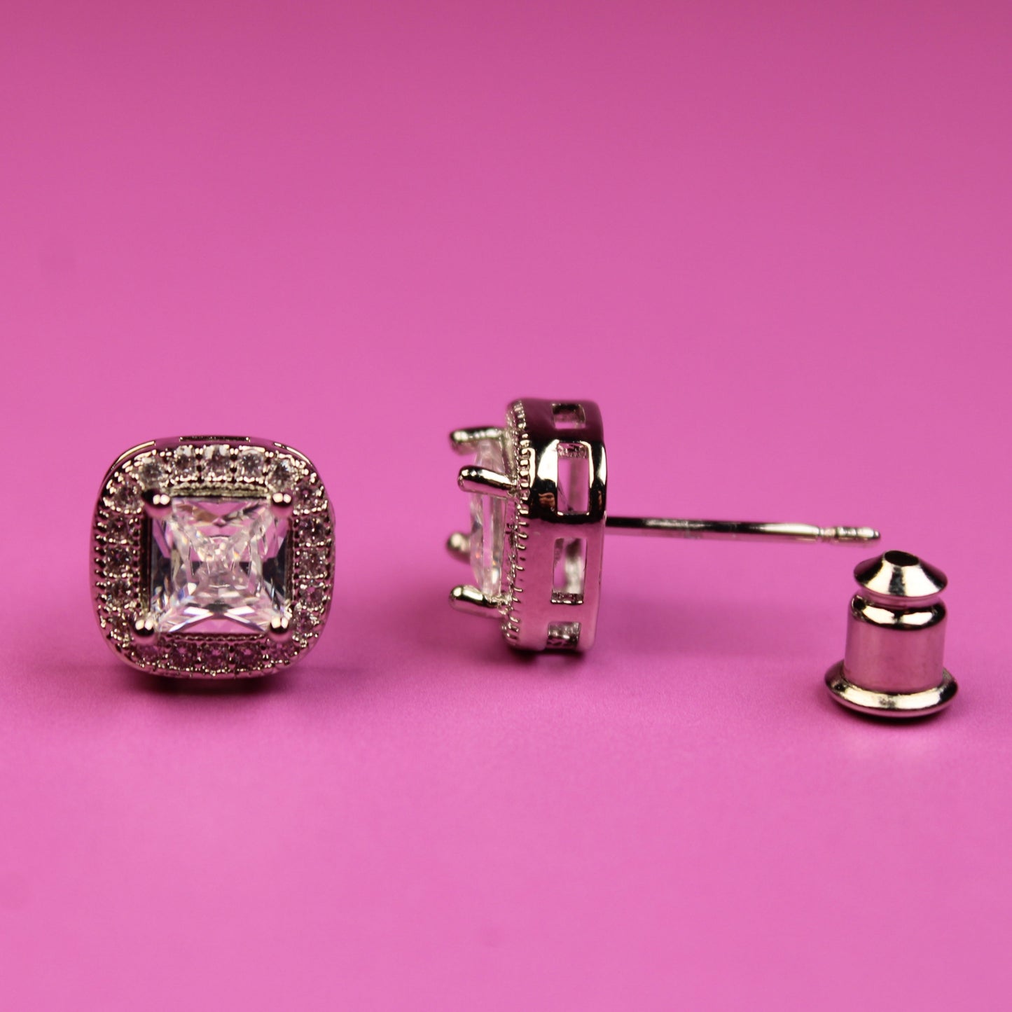 Pair of diamond earrings on a pink background