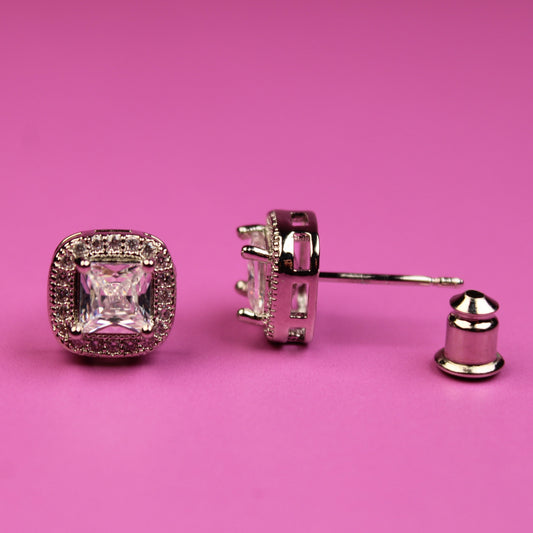 Pair of diamond earrings on a pink background