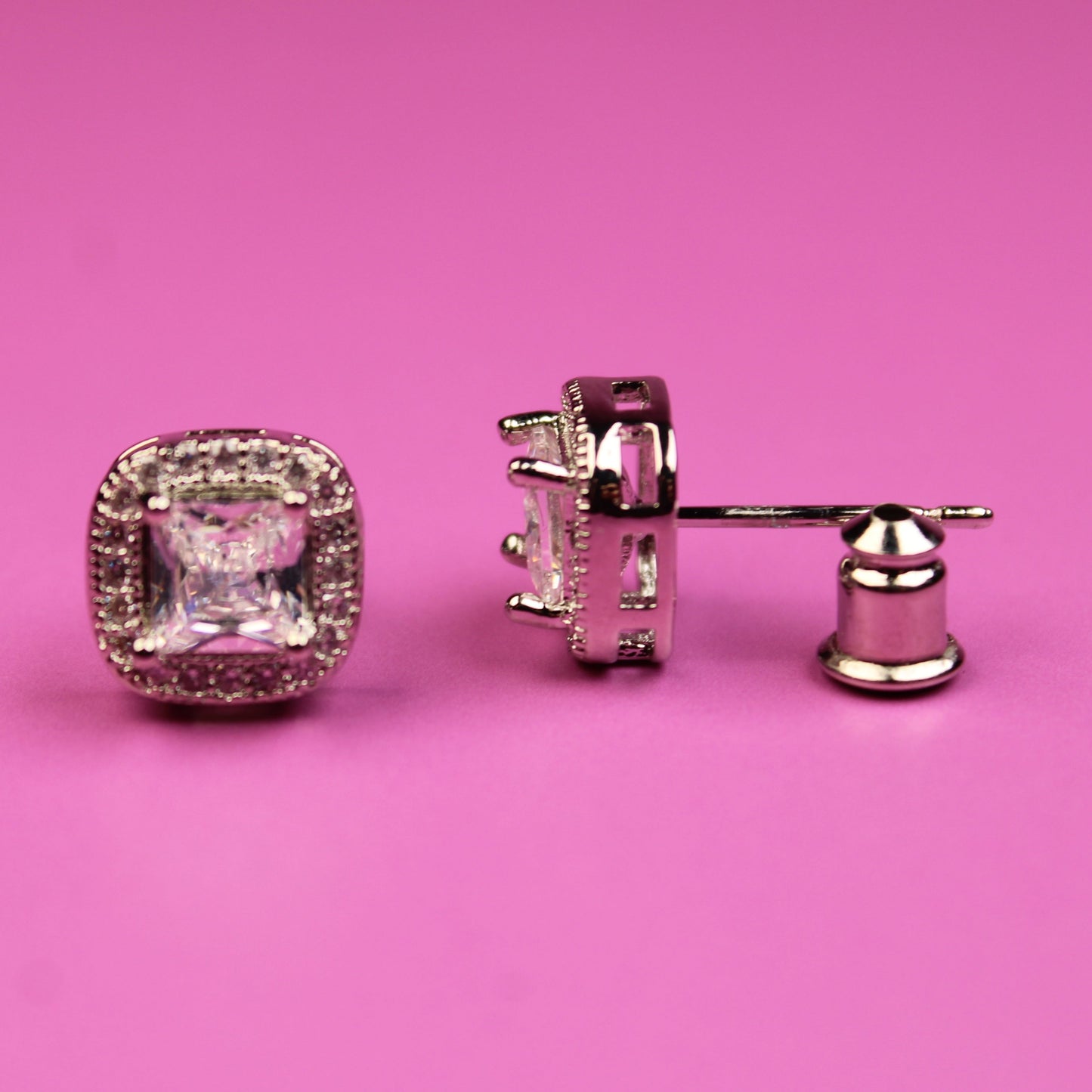 Pair of diamond earrings on a pink background