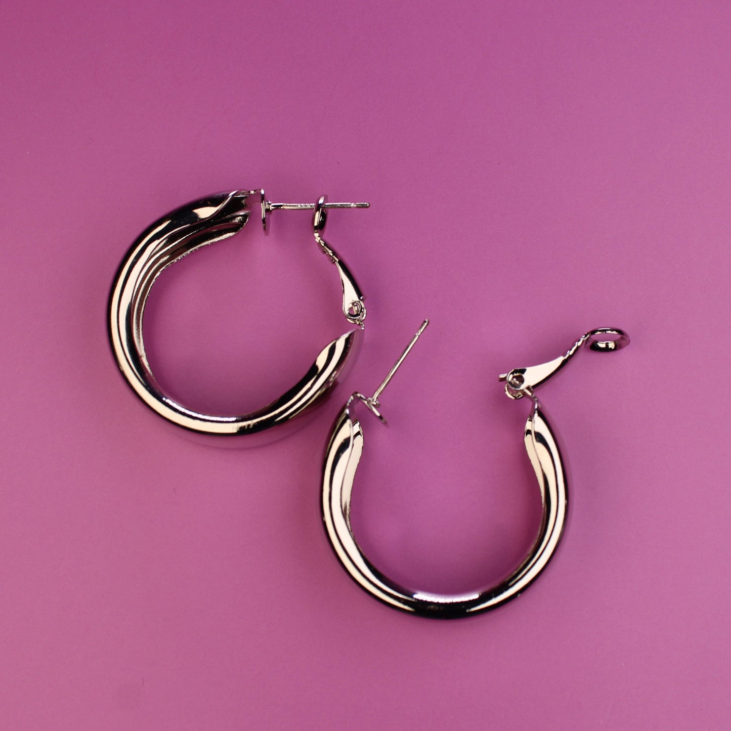 Gold hoop earrings on a pink background