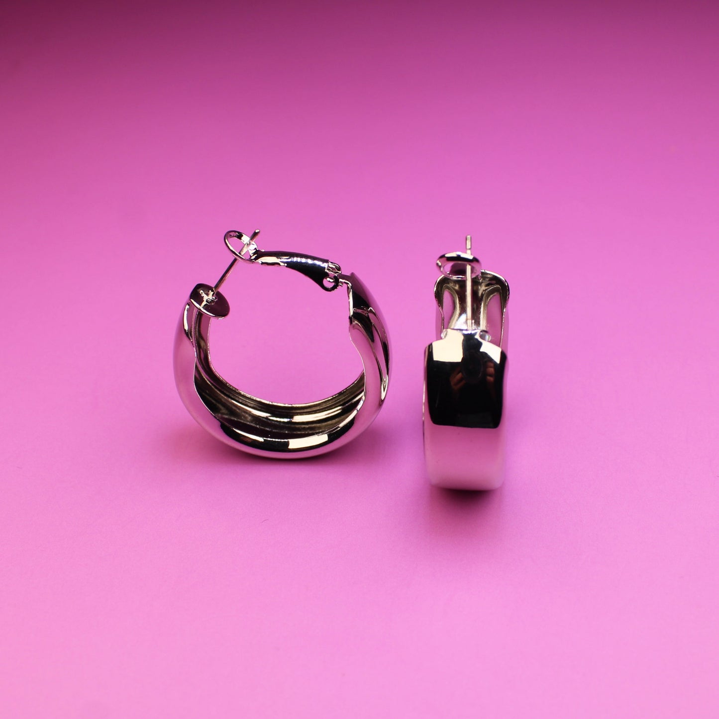Silver hoop earrings on a pink background