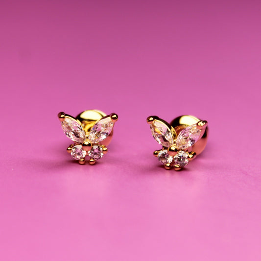 Gold butterfly-shaped earrings on a pink background