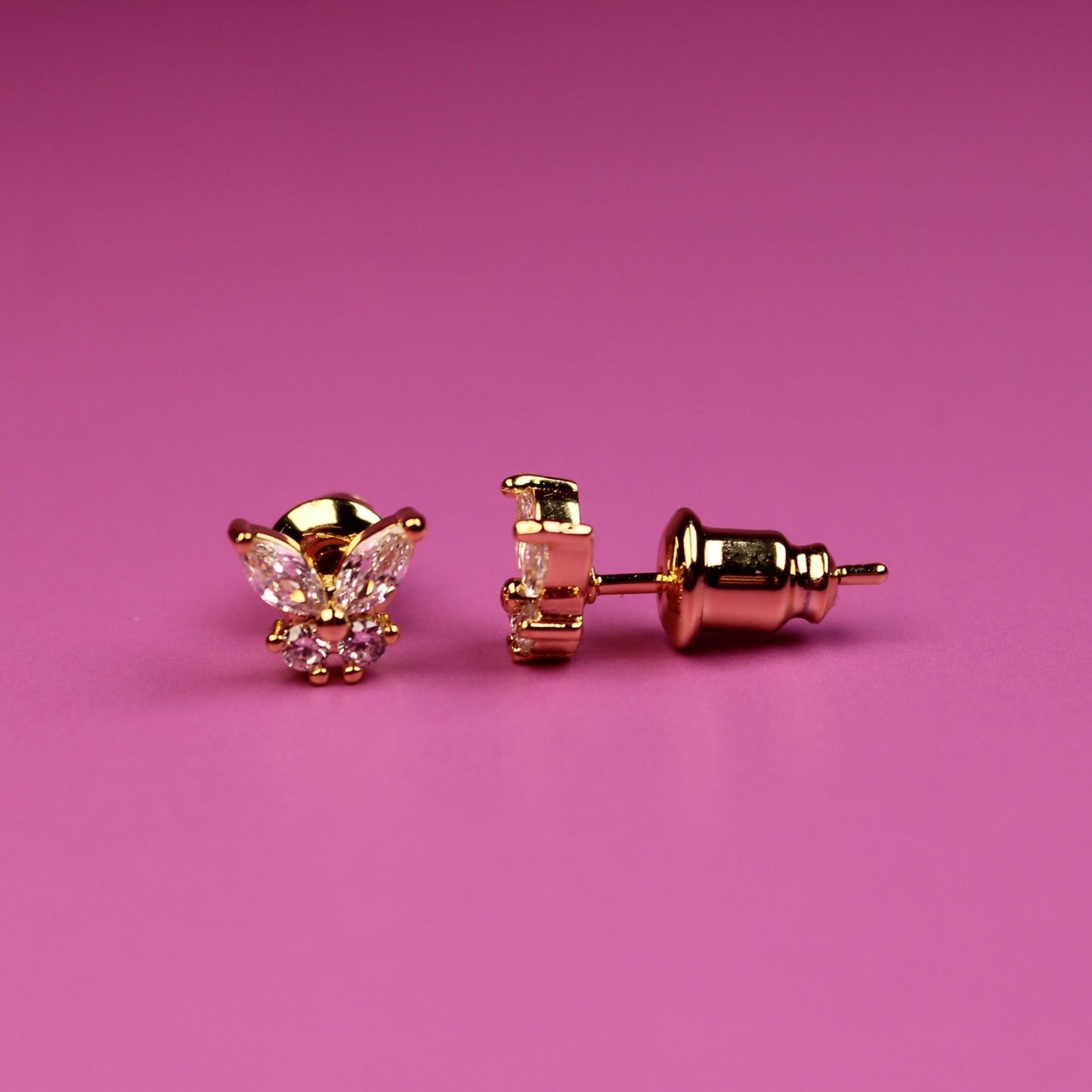 Rose gold cat-shaped earrings on a pink background